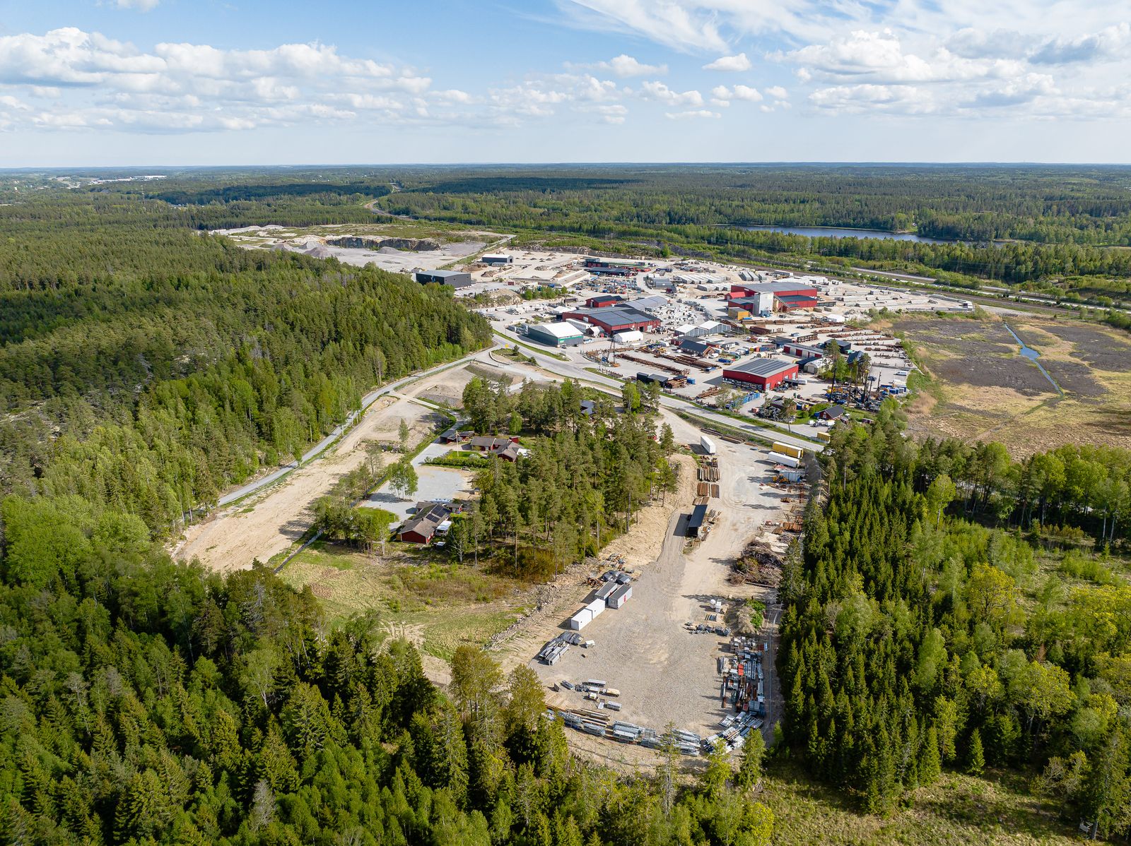 Flygbild över Snebro Gårds verksamhetsområde med industrifastigheter, uppställda lastbilssläp och omgivande skog