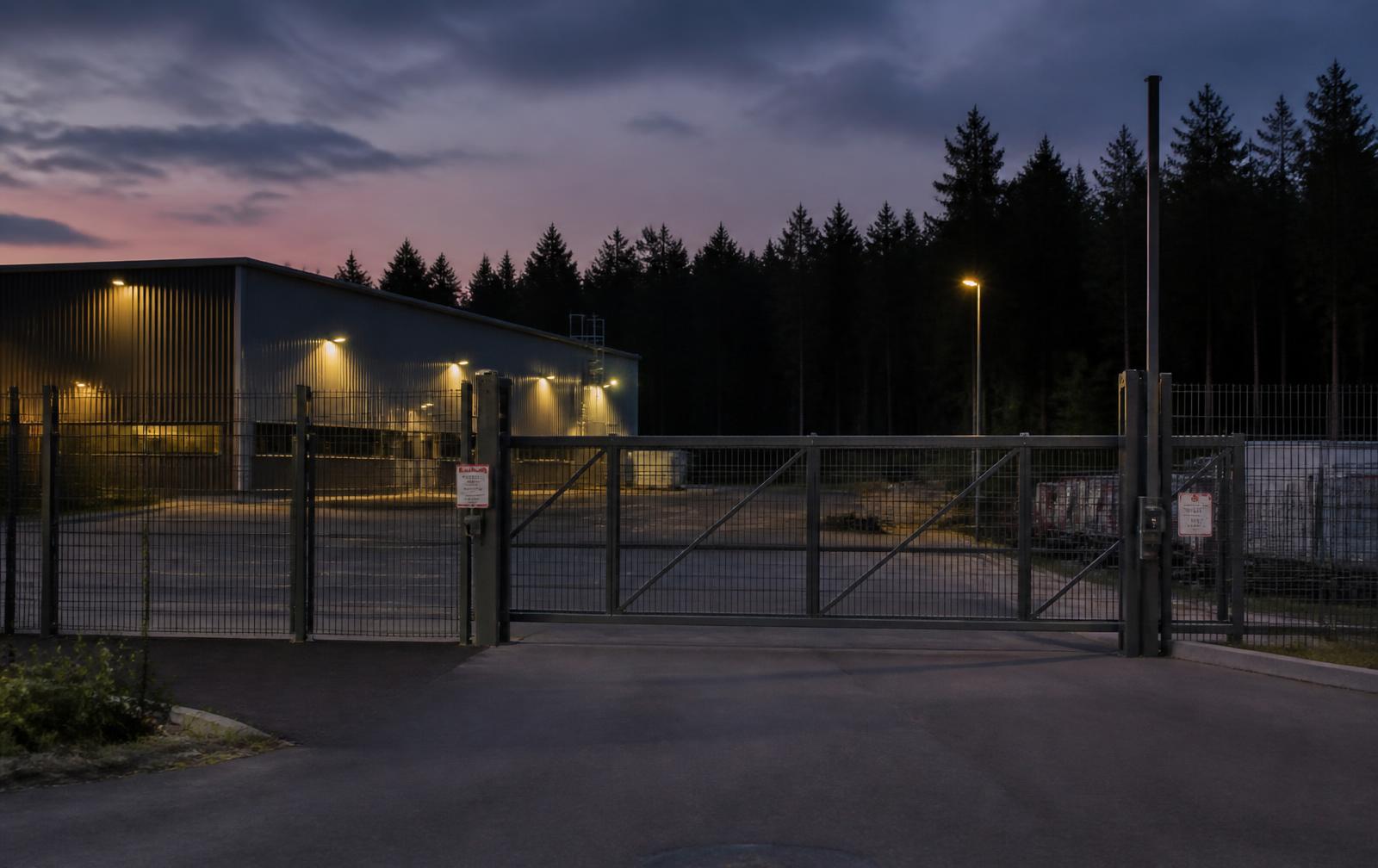 Inhägnat område med automatiserad grind vid Snebro Gård i skymning
